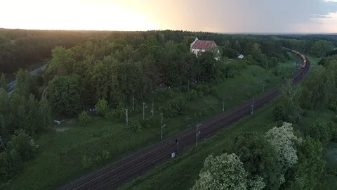 Aerial shot of cargo train running through the Church small village in the woods Stock Footage 104708008
