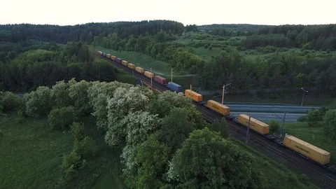 Aerial shot of cargo train running on the bridge through highway Stock Footage