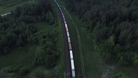 Aerial shot of cargo train running through the forests in the late evening Stock Footage 104708292
