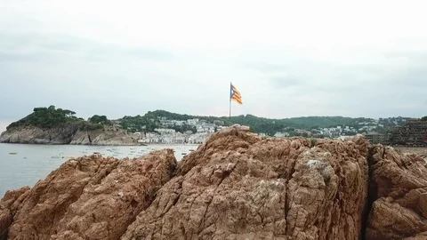 Aerial shot of Catalan flag on rock formation by boats in sea, drone ascending Stock Footage