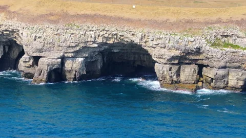 Aerial shot of a cave and cliffs on the Jurassic coastline, Dorset, UK Stock Footage 345281900