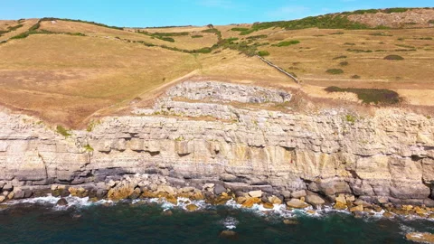 Aerial shot of cliffs and caves with rock climbers on the Jurassic coast Stock Footage 345281338