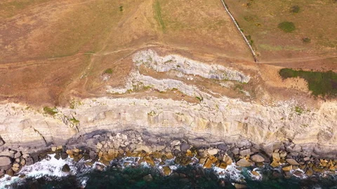 Aerial shot of cliffs and caves on the Jurassic coast in Dorset, UK Stock Footage 345281716