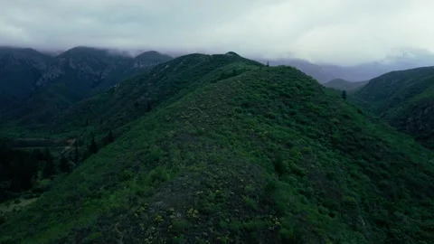 Aerial shot of cloud-covered mountain ridge above a valley dam Stock Footage 342334731