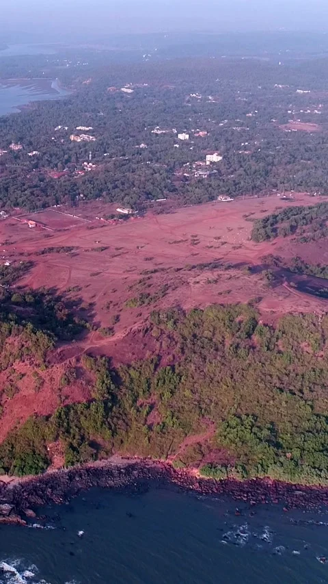 Aerial shot of coast with red soil, buildings along it and rocky beach Stock-Footage 226861484