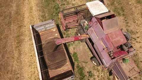 Aerial shot of a combine harvester loading a dump truck with grain in summer Stock Footage 79790844