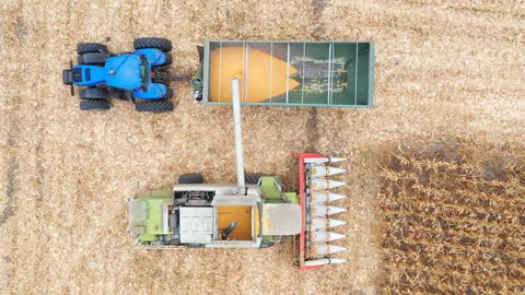 Aerial shot of combine loading off wheat grains into tractor truck. Harvester Stock Footage 143324371