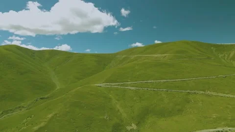 Aerial Shot of Continuous Green Grass Slope Fence Herd Path Floating Cloud in Video stock 337979921