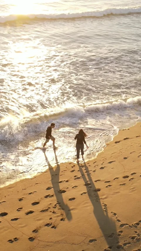 Aerial shot of a couple walking on the beach. Vertical Video. Vídeo Stock 301551853