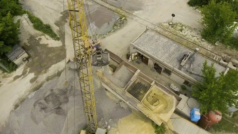 Aerial shot of crane claw loading rubble into conveyor at concrete factory Stock Footage 103546016
