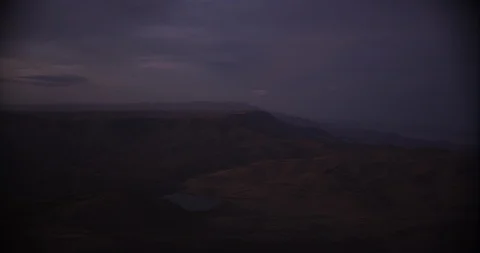 Aerial shot, day, dark sky after sunset over arid hill country with lake, drone Video stock 115196053