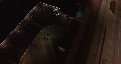 Aerial shot descending on a seedy motel at night while a patron pulls into the Stock Footage