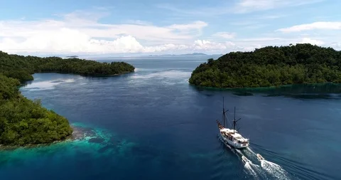 Aerial shot of diving boat going along tropical island with shallow reef Stock Footage 100218965