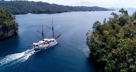 Aerial shot of diving boat navigating between rocky islands 스톡 동영상 100406803