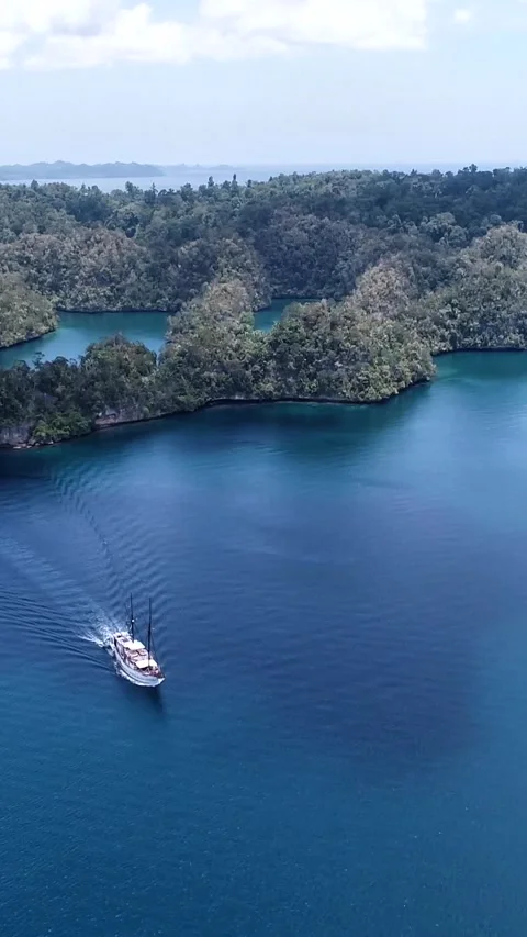 Aerial shot of diving boat navigating between rocky islands 스톡 동영상 227119775