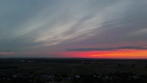 Aerial shot of a dramatic sunset over a rural landscape with colorful clouds in Stock Footage 300807930