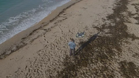 Aerial shot of drone operator flying a drone from a beach Stock Footage 132875598