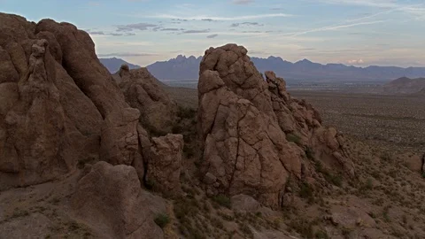Aerial shot elevating above rocky cliffside revealing sunset and mountains Video stock 89554867