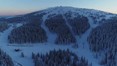 Aerial shot of empty snow covered ski slopes and pine forest after sunset Stock Footage 86115786