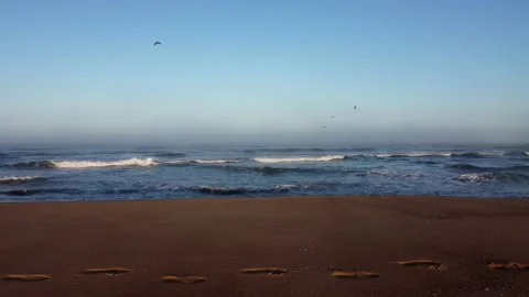 Aerial Shot fast to the left over foot prints on the beach - golden hour Stock Footage 161590372