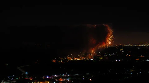 Aerial Shot Of Fireworks Exploding On Buildings In City, Drone Flying Backward Stock Footage 243885254