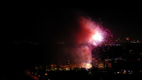 Aerial Shot Of Fireworks Exploding On Illuminated Residential Buildings, Drone Stock Footage 243881255