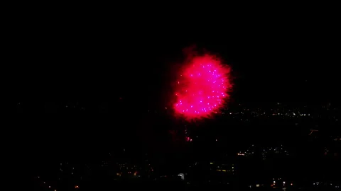 Aerial Shot Of Fireworks Exploding Over Buildings Against Sky At Night, Drone Stock Footage 243878210