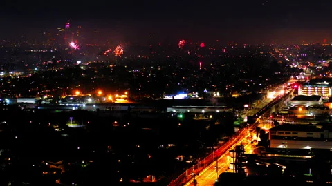 Aerial Shot Of Fireworks Exploding Over Illuminated City, Drone Flying Forward Stock Footage 243880068