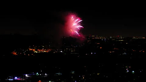 Aerial Shot Of Fireworks Exploding Over Buildings Against Sky, Drone Flying Stock Footage 243880605