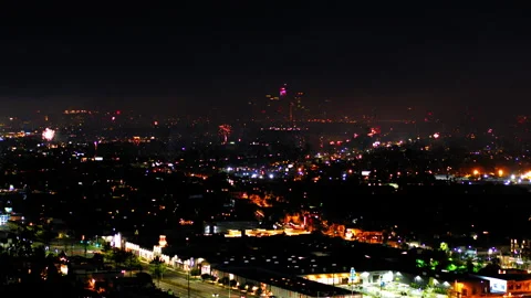 Aerial Shot Of Fireworks Exploding Over Illuminated City, Drone Flying Backward Stock Footage 243880837
