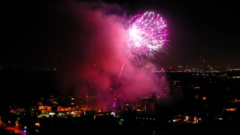 Aerial Shot Of Fireworks Exploding Over Buildings In Suburb Against Sky, Drone Stock Footage 243881655