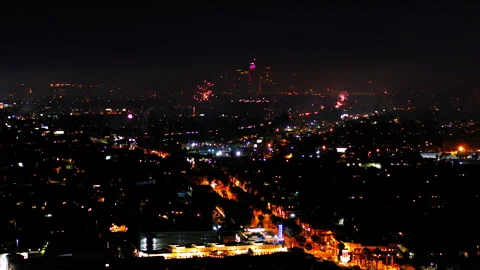Aerial Shot Of Fireworks Exploding Over Buildings In City, Drone Flying Backward Stock Footage 243884292