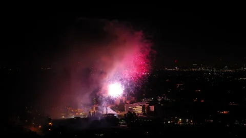 Aerial Shot Of Fireworks Exploding Over Neighborhood In City Against Sky, Drone Stock Footage 244015610