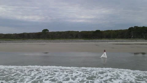 Aerial Shot Fly Over Waves Towards Woman Walking on Beach Stock Footage 147305937