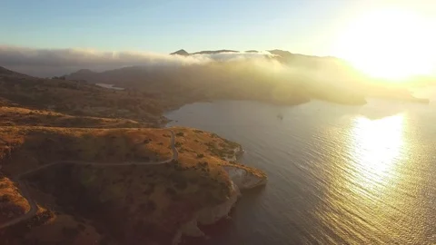 Aerial shot flying backwards overlooking the coastline of an island at sunset. Video stock 88670848