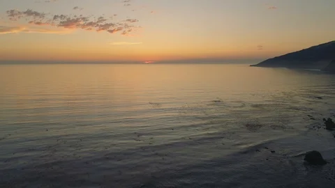 Aerial shot flying forward over the ocean, smooth glassy water at sunset. Dusk. Video stock 87728655