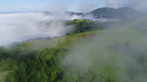 Aerial shot. Flying through the clouds over green hills covered with grass and Stock Footage 142935312