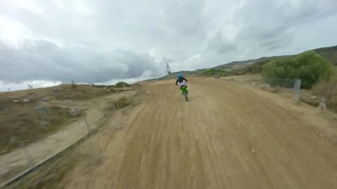 Aerial shot with FPV drone chasing a green motocross bike on track day Video stock 257795692