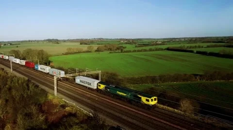 Aerial shot of freight train rolling through UK countryside Stock Footage 58535300