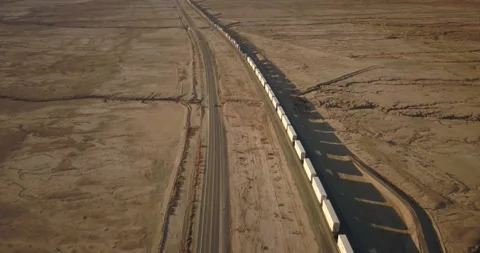 Aerial shot of freight train at sunset moving through the desert Video stock 276854681