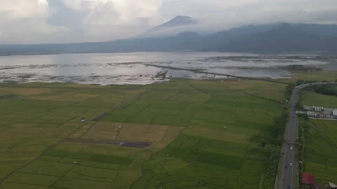 Aerial shot of green fields next to lake with mountain background in 4K Stock Footage 200872689