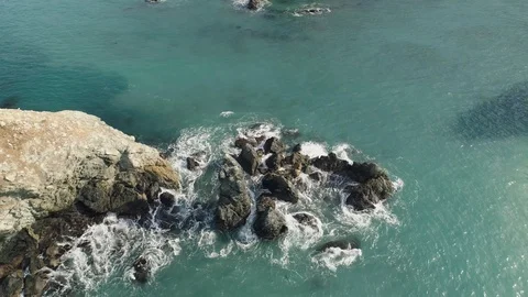 Aerial shot looking down and revolving around rocks in the ocean. 库存影片 88188126