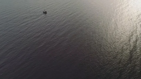 Aerial shot looking down at a boat in water with sun reflecting off water. Video stock 104773146