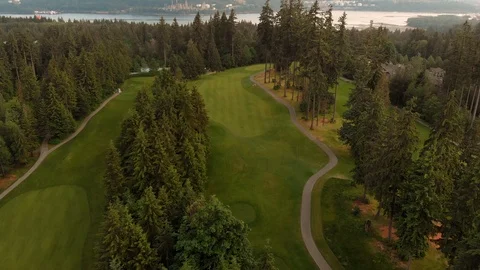 An aerial shot looking down a golf course fairway nestled in a forest with a Stock Footage 108910568