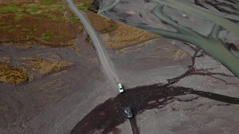 Aerial shot looking down at two vehicles crossing a small river. Video stock 157241044
