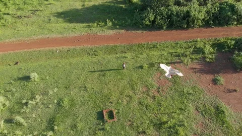 Aerial shot looking down on a young boy flying a kite in the evening sun. Stock Footage 108473386