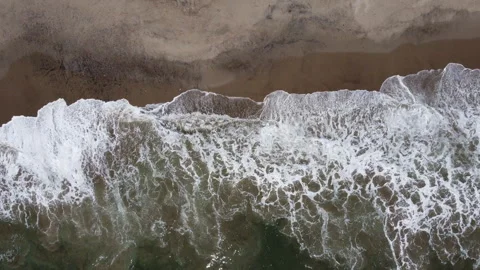 Aerial shot lowering down to beach waves crashing Stock Footage 271104055