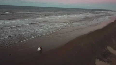 Aerial shot of man and woman walking on a beach Stock Footage