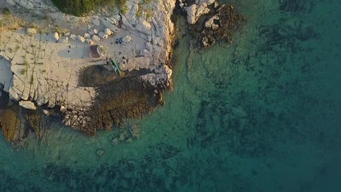 Aerial shot of man jumping to blue ocean during calm and colorful sunrise Stock Footage 101338464