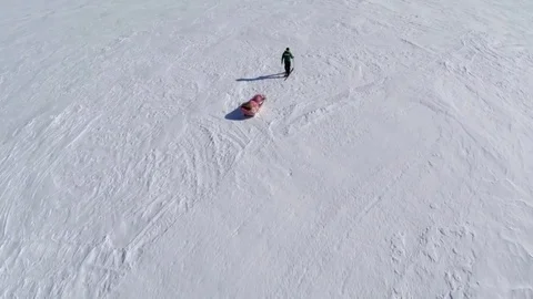 Aerial shot of a man pulling his sled across snow Stock Footage 79978847